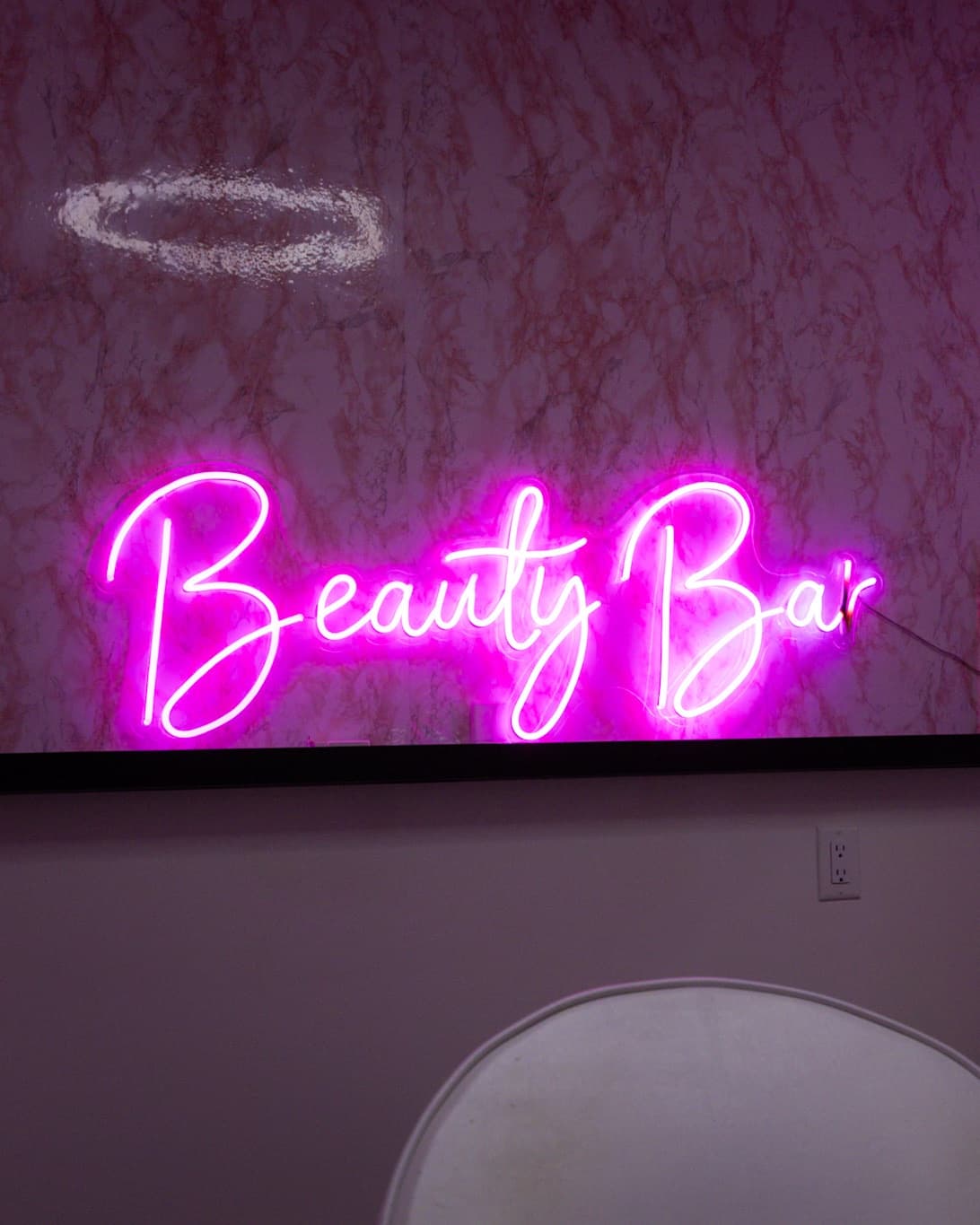Pink "Beauty Bar" neon sign reflected in a tall mirror at House of Snob in Edmonton