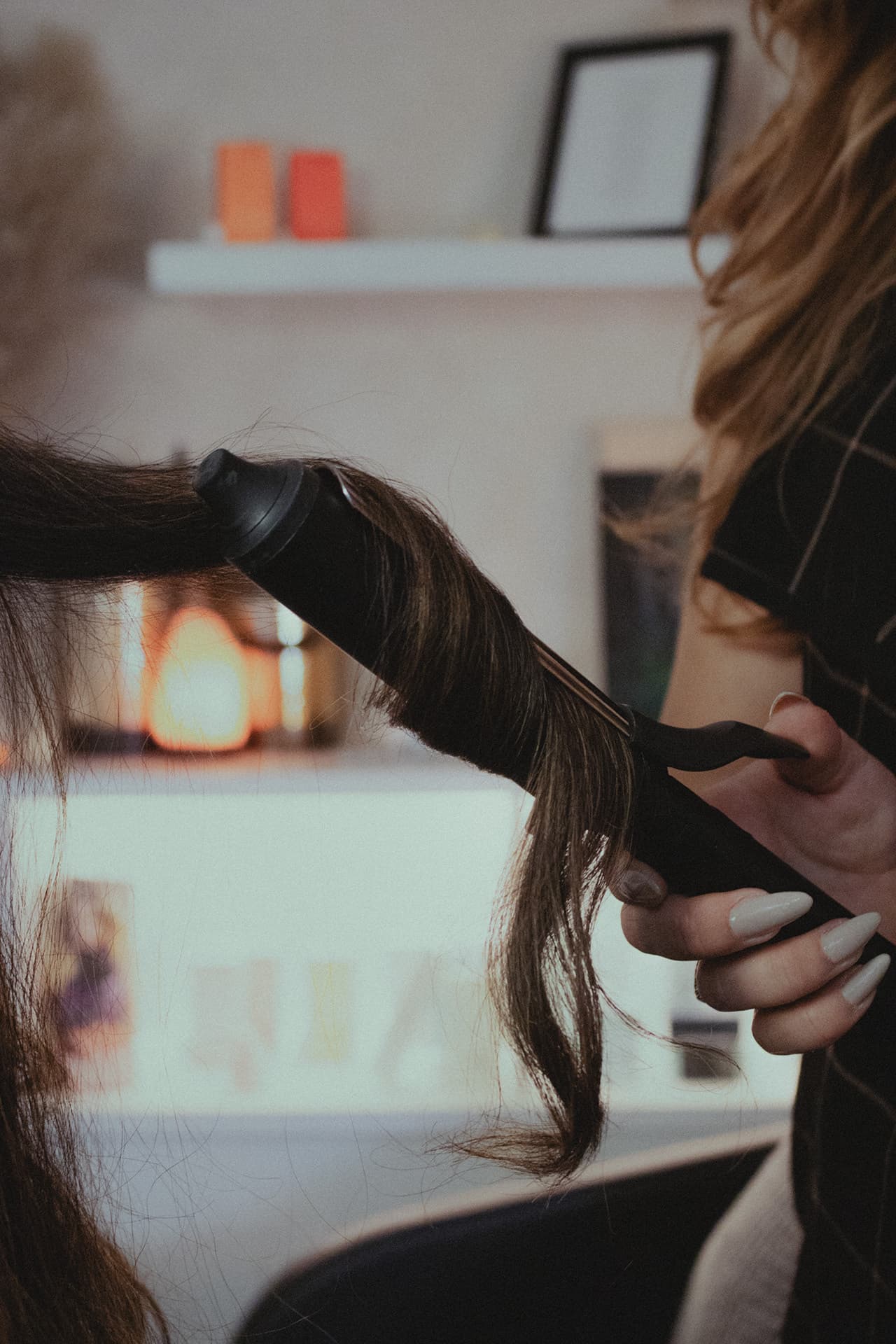 Long brunette hair wrapped around a curling iron, held by a stylist's hand in The Sanctuary